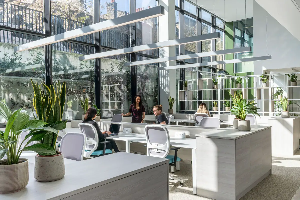 People sitting at the hot desk area with large wall windows at Queen Mary University Enterprise Zone - on Tally Workspace