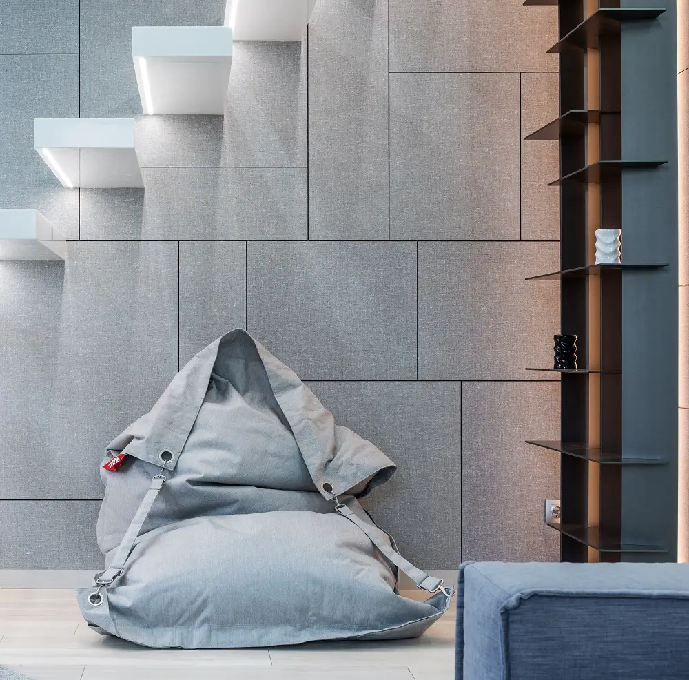 gray plush looking bean bag chair under a floating staircase design