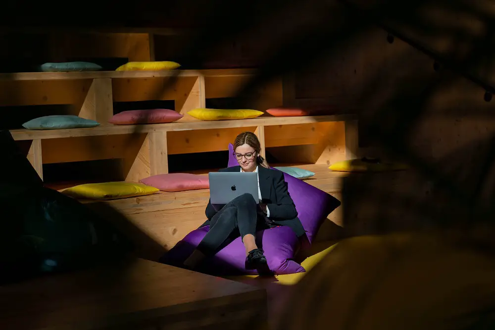 girl with laptop staying on a purple bean bag chair