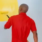A professional painter painting an interior wall with a roller