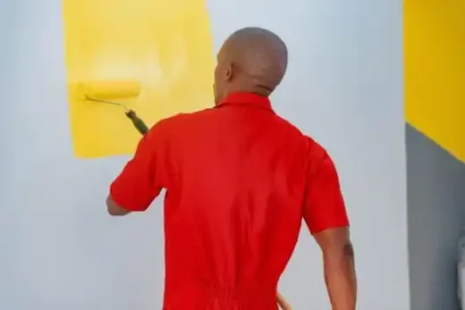 A professional painter painting an interior wall with a roller