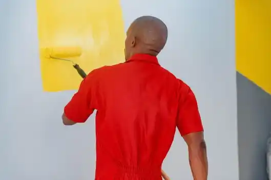 A professional painter painting an interior wall with a roller